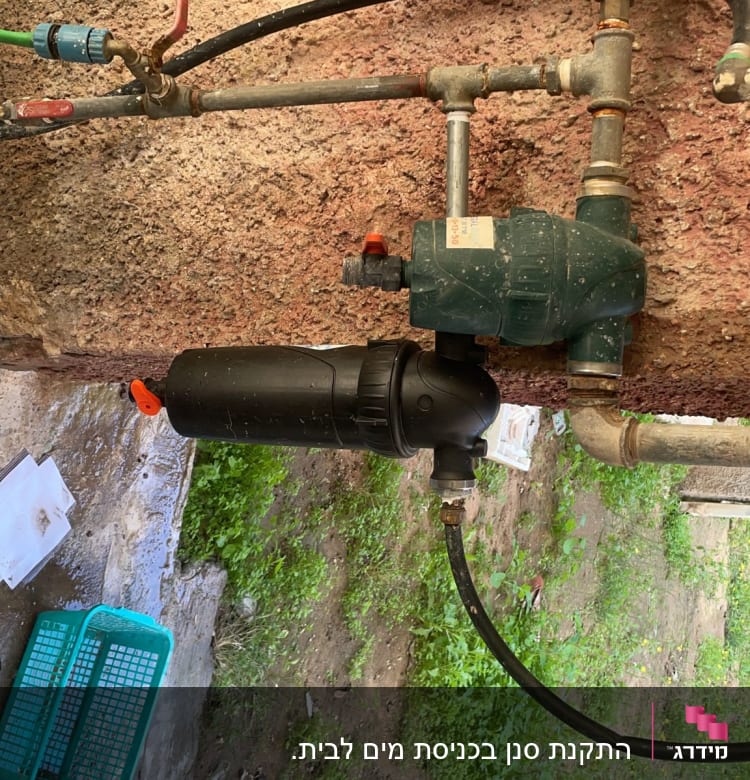 צנרת מים עם ברזים ומד מים על קיר